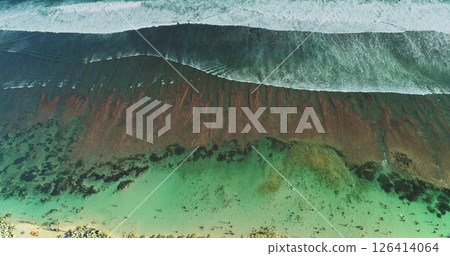 Stunning drone footage captures the mesmerizing beauty of turquoise ocean waves gracefully crashing onto the shore, revealing a captivating blend of colors and textures beneath the surface Stunning drone footage captures the mesmerizing beauty of turquoise ocean waves gracefully crashing onto the shore, revealing a captivating blend of colors and textures beneath the surface 126414064