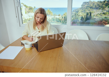 Woman Working Remotely in Home Office With Scenic View and Minimalist Decor Woman Working Remotely in Home Office With Scenic View and Minimalist Decor 126414132