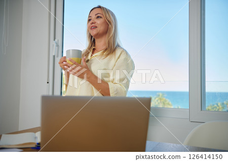 Woman Enjoying Coffee Break While Working Remotely With Ocean View Woman Enjoying Coffee Break While Working Remotely With Ocean View 126414150