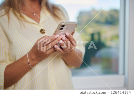 Close-Up of Woman Holding Smartphone in Relaxed Setting Close-Up of Woman Holding Smartphone in Relaxed Setting 126414154