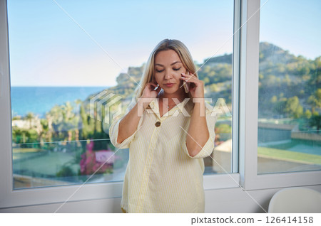 Woman on a Call in a Bright Room Overlooking a Scenic Landscape Woman on a Call in a Bright Room Overlooking a Scenic Landscape 126414158