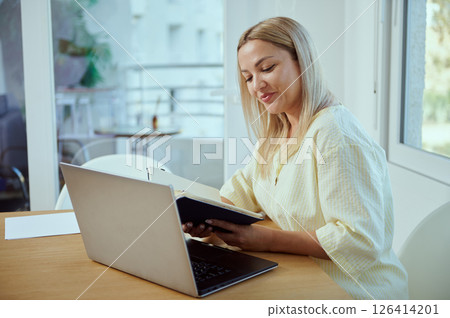 Woman Working Remotely on Laptop in a Comfortable Home Office Environment 126414201