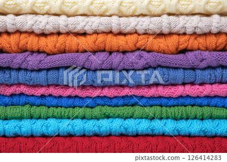 Abstract knitted background from set of multicolored knitted clothes stacked. Space for text. Knitting warm clothes, blankets and blankets. Concept of home needlework 126414283