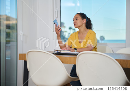 Casual Home Workspace with Woman Using Smartphone and Taking Notes Casual Home Workspace with Woman Using Smartphone and Taking Notes 126414308
