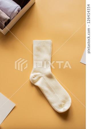 Soft cream colored sock pair placed on warm yellow background. Ideal for comfort wear promotions, sock collections, or joyful lifestyle imagery. Vertical. Soft cream colored sock pair placed on warm yellow background. Ideal for comfort wear promotions, sock collections, or joyful lifestyle imagery. Vertical. 126414354