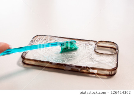 Transparent phone case being cleaned with a toothbrush and soap. Before and after use. Eco and reuse concept 126414362