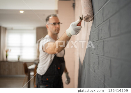 Man in White Shirt and Black Pants Working on a Wall 126414399