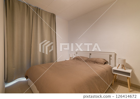 Full view of minimalist bedroom with white bed frame, neutral bedding and two small nightstands Full view of minimalist bedroom with white bed frame, neutral bedding and two small nightstands 126414672