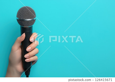 Close-Up of Hand Holding a Microphone Against a Blue Background 126415671