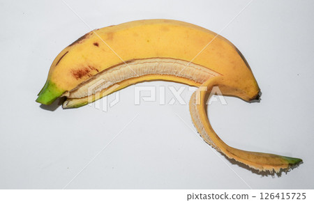 Ripe banana peeled in half on a white background. Concept of fresh tropical snack, healthy food. Ripe banana peeled in half on a white background. Concept of fresh tropical snack, healthy food. 126415725