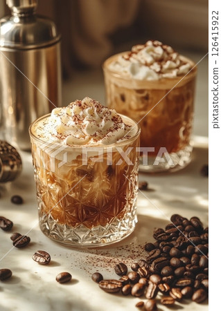 Two iced coffee beverages with whipped cream and coffee beans in sunlight 126415922