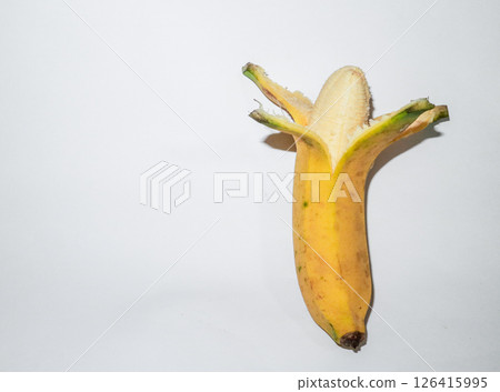 Ripe banana peeled in half on a white background. Concept of fresh tropical snack, healthy food. 126415995