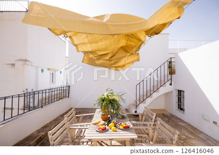 Sunlit rooftop table set for Mediterranean lunch Sunlit rooftop table set for Mediterranean lunch 126416046