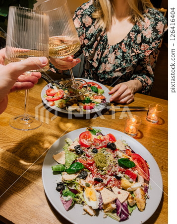 Intimate moment during dinner with wine glasses, intimate evening meal with salad and candles, intimate home scene with love and flavor, intimate night together. Romantic dinner with wine and salad Intimate moment during dinner with wine glasses, intimate evening meal with salad and candles, intimate home scene with love and flavor, intimate night together. Romantic dinner with wine and salad 126416404