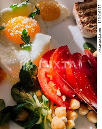 Healthy breakfast featuring fried eggs with salt and parsley, sliced tomatoes, chickpeas, fresh corn salad, and toasted bread, offering nutritious start to day. Nutritious morning meal, fried eggs Healthy breakfast featuring fried eggs with salt and parsley, sliced tomatoes, chickpeas, fresh corn salad, and toasted bread, offering nutritious start to day. Nutritious morning meal, fried eggs 126416415