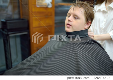Portrait of a teenager with Down syndrome in a barbershop 126416498
