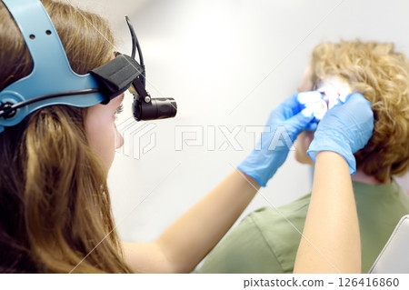 A patient is seen by an otolaryngologist. A professional ENT doctor examines a patient. An otolaryngologist examines a patient's inner ear using an otoscope 126416860