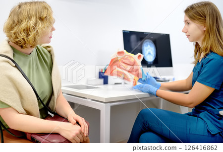 The otolaryngologist explains to the patient about his illness at the appointment. A professional ENT doctor demonstrates a model of the human nose. Treatment of inflammation disease of nose. 126416862