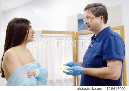 Doctor mammologist examines woman breasts. Correcting the shape of the breast - lift, reduction, reconstruction, augmentation. 126417001