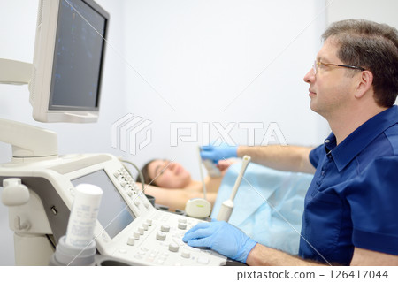 Mammologist doctor examines a woman breasts and lymph nodes using ultrasound. Mammography and ultrasound scanning are main methods of instrumental diagnosis of mammary glands. Breast cancer Mammologist doctor examines a woman breasts and lymph nodes using ultrasound. Mammography and ultrasound scanning are main methods of instrumental diagnosis of mammary glands. Breast cancer 126417044