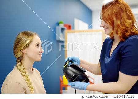 Neurologist performing positional testing of patient using videonystagmography . VNG testing uses goggles with infrared cameras to track eye movements, and can help to determine if the patient is 126417133