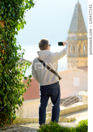 The tourist takes a photo of the landmark on his smartphone during a trip The tourist takes a photo of the landmark on his smartphone during a trip 126417142