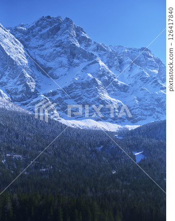 Snow-covered mountains rise majestically under a clear blue sky in winter landscape Snow-covered mountains rise majestically under a clear blue sky in winter landscape 126417840