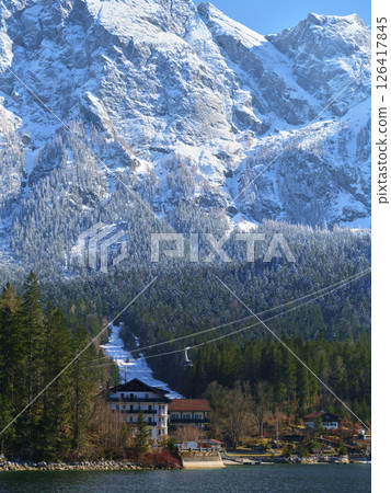 Stunning winter landscape featuring snow-capped mountains and a scenic lake beneath a clear blue sky 126417845