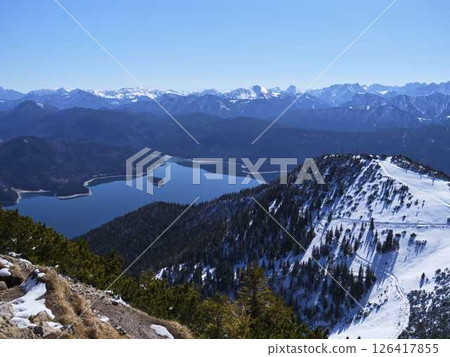 Mountain view showcasing snow-covered peaks and a serene lake on a clear day in the Alps Mountain view showcasing snow-covered peaks and a serene lake on a clear day in the Alps 126417855