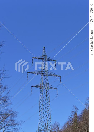 Large power transmission tower stands against a clear blue sky in a rural landscape during daylight hours Large power transmission tower stands against a clear blue sky in a rural landscape during daylight hours 126417868