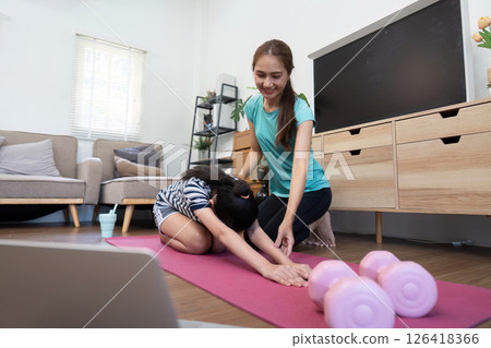 Mother and Daughter Wellness. Stretching and yoga session at home with pink dumbbells. Mother and Daughter Wellness. Stretching and yoga session at home with pink dumbbells. 126418366