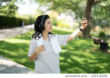 Wellness and joy: Elderly woman taking a selfie while walking 126418406
