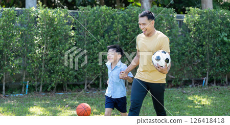 Activity: Father and Son Playing Soccer Together in the Park Activity: Father and Son Playing Soccer Together in the Park 126418418