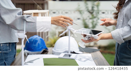 Sustainability engineer exchanging renewable resource ideas outdoors Sustainability engineer exchanging renewable resource ideas outdoors 126418435