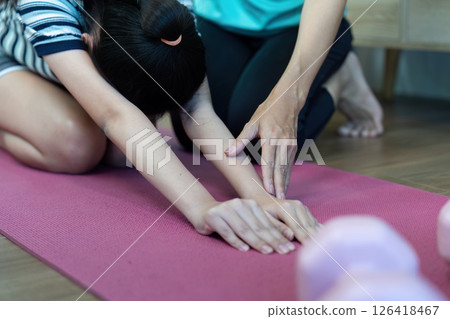 Mother and Daughter Wellness. Engaging in stretching exercises with pink dumbbells at home. Mother and Daughter Wellness. Engaging in stretching exercises with pink dumbbells at home. 126418467