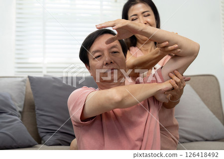 Wellness and Care. Elderly couple practicing stretching exercises at home. 126418492