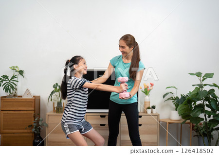 Mother and Daughter Fitness. Sharing a Weightlifting Experience at Home. 126418502