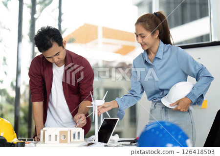 Engineer Collaboration on Sustainable Project. Team discussing renewable energy models in modern office. 126418503