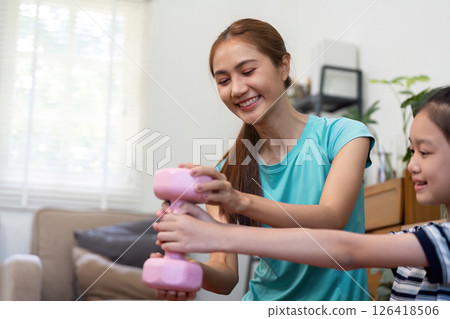 Wellness in Fitness: Mother and daughter exercising with pink weights Wellness in Fitness: Mother and daughter exercising with pink weights 126418506