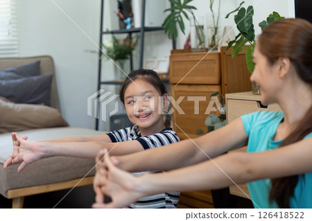 Mother and Daughter Wellness. Engaging in Stretching Exercises Together at Home. 126418522