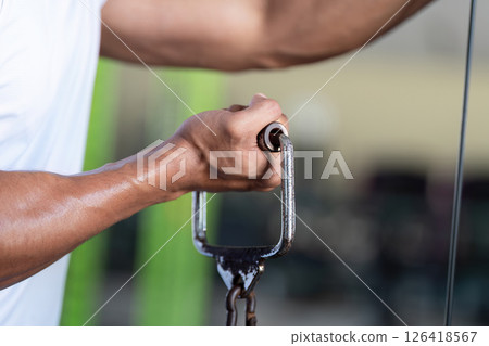Wellness and Fitness. Close-up of a strong hand gripping gym equipment during a workout session. Wellness and Fitness. Close-up of a strong hand gripping gym equipment during a workout session. 126418567
