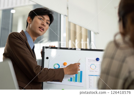 Effective Business Presentation. Male professional presenting budget data with confidence. Effective Business Presentation. Male professional presenting budget data with confidence. 126418576