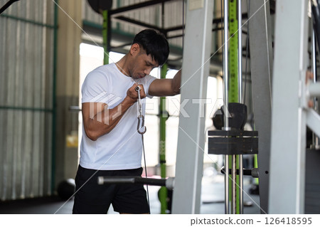 Wellness through Strength Training. Young man focused on cable machine workout in gym. 126418595