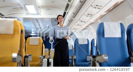 Business travel: Asian woman walking in airplane aisle with suitcase Business travel: Asian woman walking in airplane aisle with suitcase 126418597