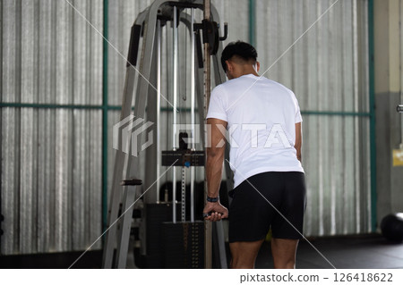 Wellness through Fitness. Young man performing back exercise on gym machine. Wellness through Fitness. Young man performing back exercise on gym machine. 126418622