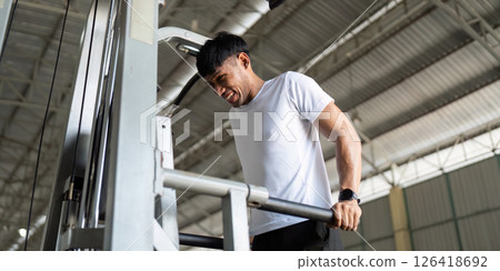 Wellness Focus. Man exerting effort on gym machine for strength training. Wellness Focus. Man exerting effort on gym machine for strength training. 126418692