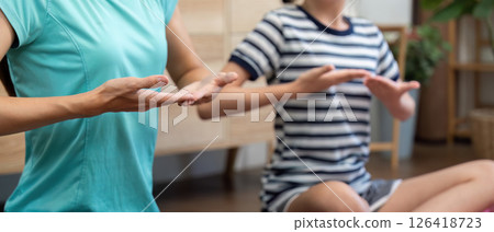 Wellness routine of mother and daughter practicing mindful yoga 126418723