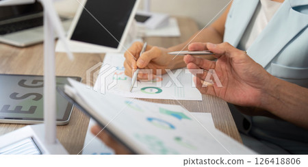 Sustainability analysis: Close-up of hands working on ESG documents 126418806