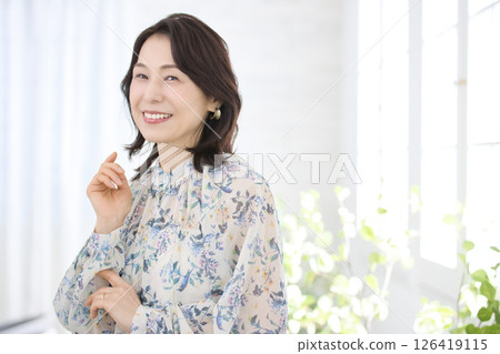 A smiling middle-aged woman wearing a floral blouse A smiling middle-aged woman wearing a floral blouse 126419115