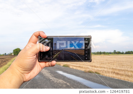 Capturing a scenic road landscape rural area smartphone open space handheld travel inspiration Capturing a scenic road landscape rural area smartphone open space handheld travel inspiration 126419781